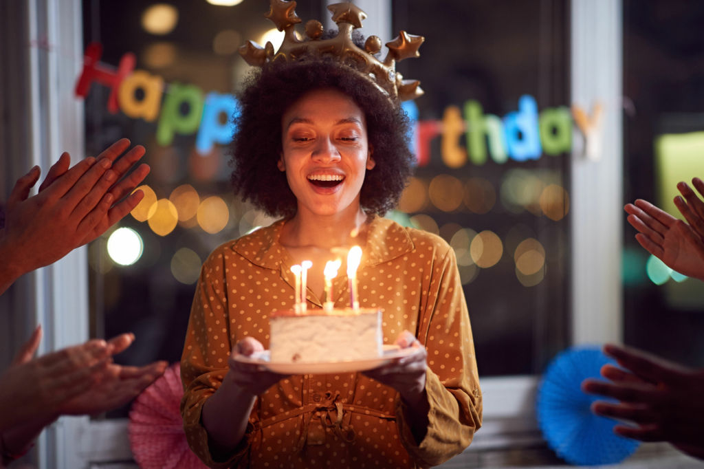 Adobe Stock - Photo d'illustration - Une jeune femme sur le point de souffler ses bougies d'anniversaire.