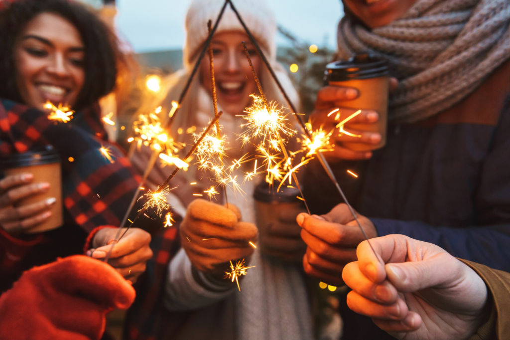 Adobe Stock - Photo d'illustration - Un groupe de personnes rassemblées tenant des feux de Bengale et des boissons chaudes dans leurs mains.