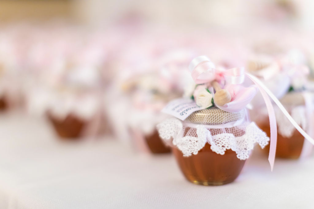 Adobe Stock - Photo d'illustration - Des pots de miel scellés par un ruban en guise de cadeaux pour les invités.