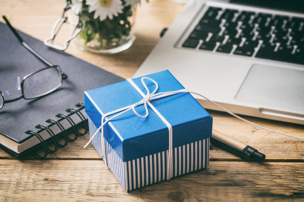 Adobe Stock - Photo d'illustration - Petite boîte cadeau bleue posée sur un bureau... de quoi faire plaisir à ses collègues.