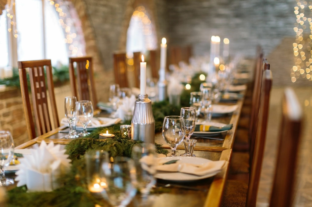 Adobe Stock - Photo d'illustration - Longue tablée, illuminée par une vaisselle raffinée et des branches en guise de chemin de table.