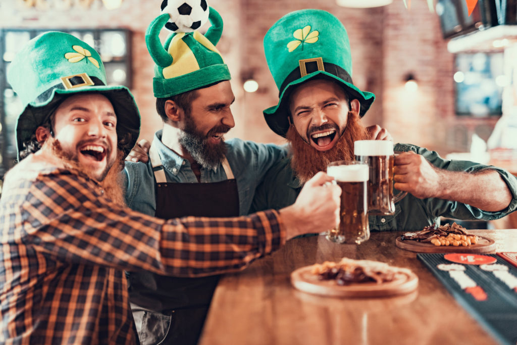 Adobe Stock - Photo d'illustration - Déguisés en farfadets à barbe rousse, ces trois amis fêtent la Saint Patrick, un pichet de bière à la main.