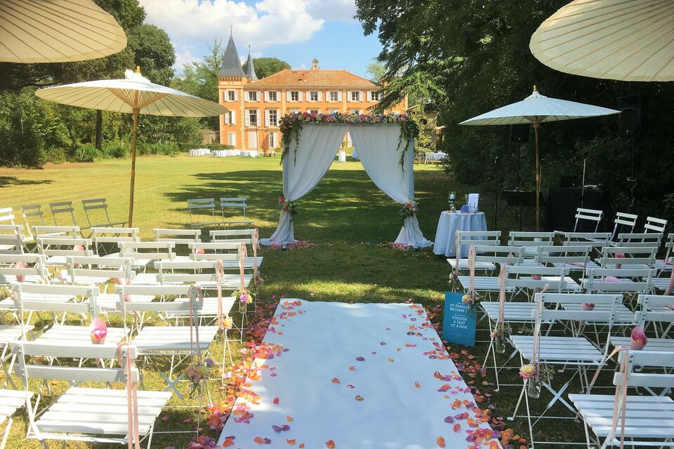 ABC Salles - Parasols, chaises et arches fleuries ornent le parc du château de Roquelune, pour une cérémonie de mariage romantique.
