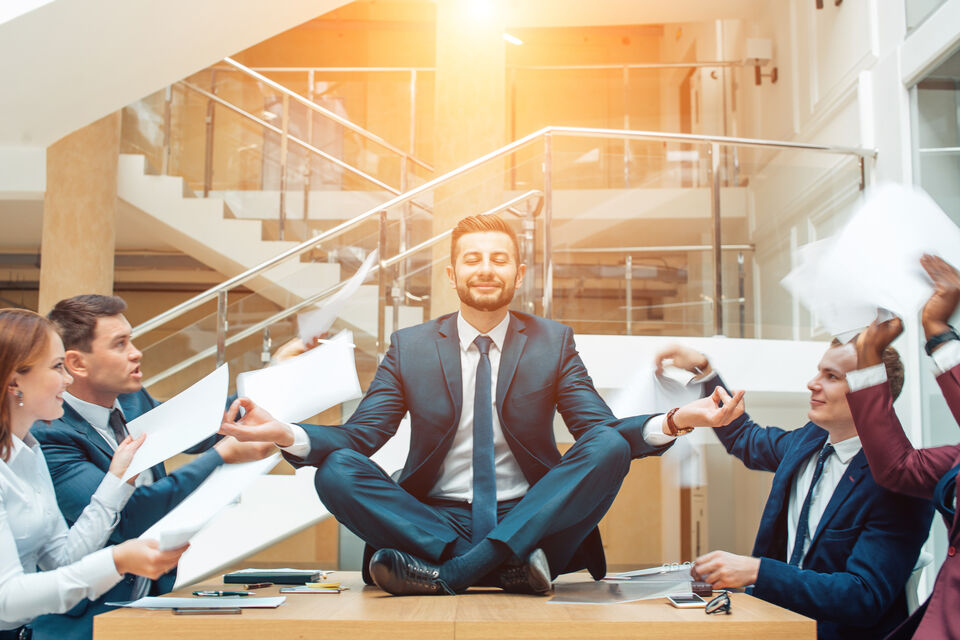 Adobe Stock - photo d'illustration - Rester calme et faire face au stress comme ce salarié d'entreprise faisant de la méditation alors que ses collègues le sollicite.