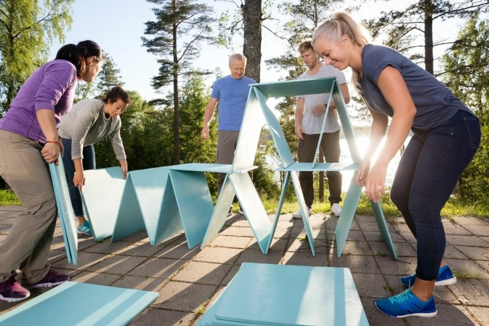 Adobe Stock - Photo d'illustration - Un groupe de collègues construit un château de cartes géant à l'occasion d'un moment de team building.<br>