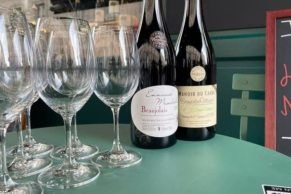 ABC Salles - par Camille Gouin - Bouteilles de Beaujolais nouveau présentées sur une table, devant l'entrée de la cave Le Repaire de Bacchus 
