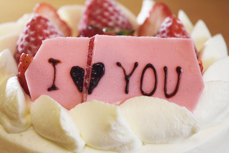 Adobe Stock - photo d'illustration - Un gâteau avec du glaçage et des fraise. Il y a un rectangle de sucre rose, sur lequel il y a noté 