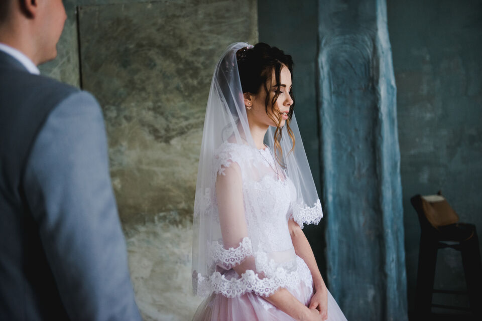 Adobe Stock - photo d'illustration - Les yeux clos et la tête tournée vers la fenêtre, une jeune mariée attend de découvrir son époux pour la première fois. C'est à l'abri du regard des invités que s'organise la tradition du first look, aussi appelé premier regard, échangé par de jeunes marié.e.s !<br>