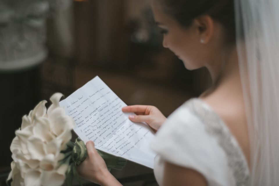 Pexels - Photo d’illustration - Une mariée émue, vêtue d'une robe blanche immaculée, tient délicatement sa lettre d'intention, l'émotion dans ses yeux.