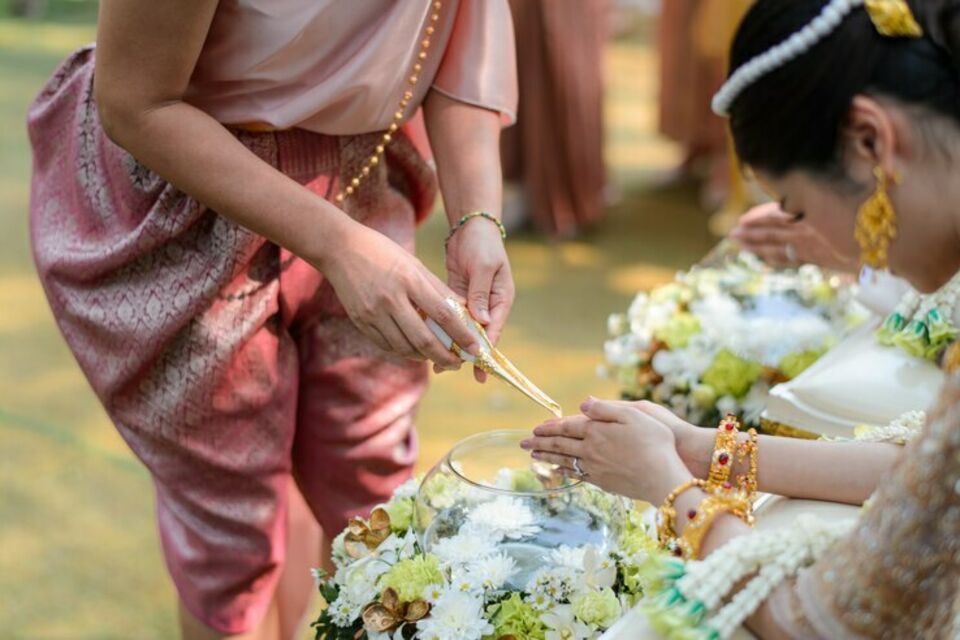 Freepik - Photo d'illustration - Un moine thaïlandais effectuant le rituel de l'eau, versant des bénédictions sur les mains jointes de la mariée lors d'une cérémonie de mariage traditionnelle.