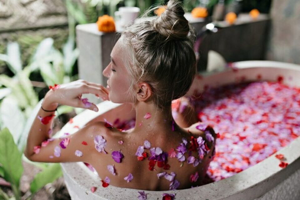 Freepik - Photo d'illustration - Future mariée en plein moment de détente, entourée de pétales de fleurs dans un bain relaxant, symbolisant la tradition du rituel de beauté.