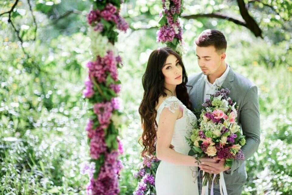Freepik - Photo d'illustration - Jeunes mariés épanouis posant dans un cadre naturel somptueux, entourés de fleurs éclatantes et de verdure luxuriante, capturant l'essence de leur amour et de la beauté du moment.