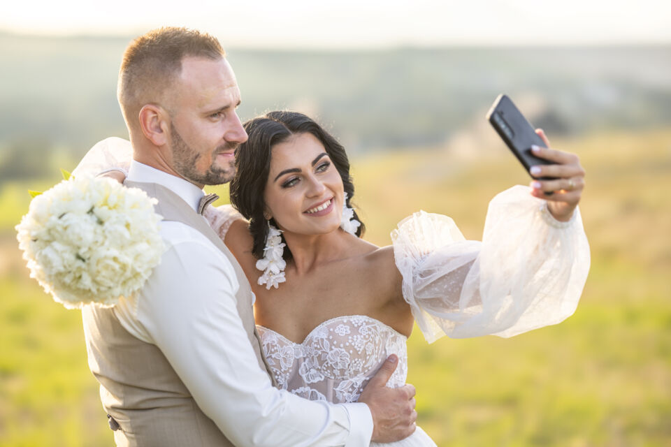 Adobe Stock - Photo d'illustration - Jeune couple de mariés qui pose pour un selfie afin de le partager avec leurs proches et leurs invités.