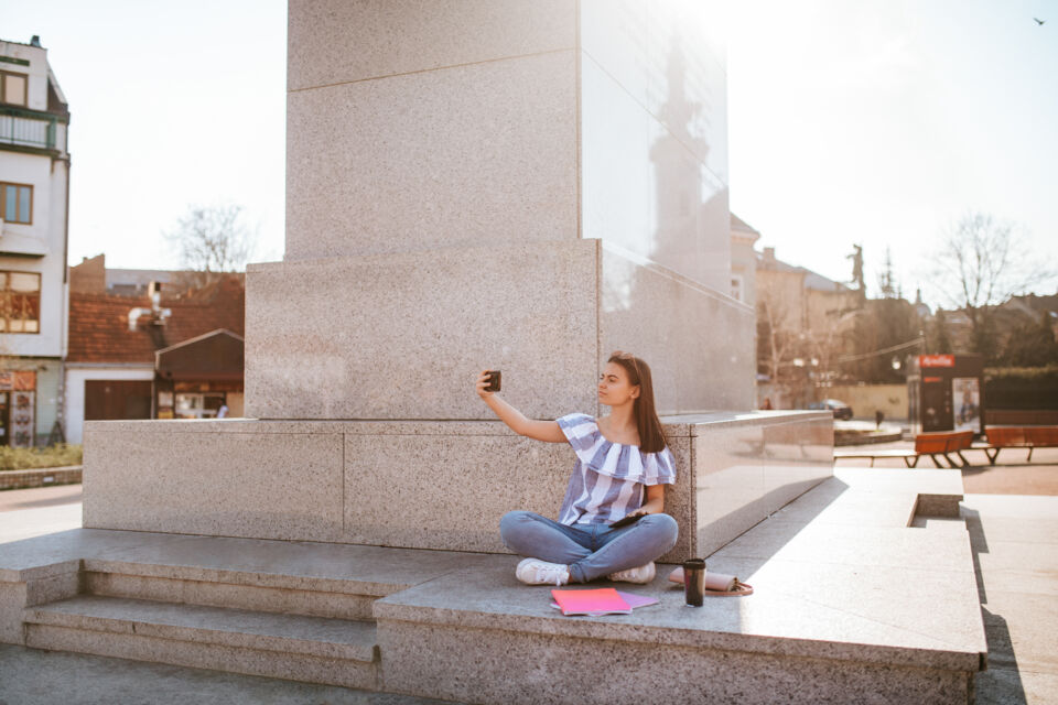 Adobe Stock - Photo d'illustration - Une jeune femme prend des photos près d'un monument célèbre, préparant un love note avec un message spécial qu'elle enverra aux futurs mariés pour célébrer leur amour à travers le monde.