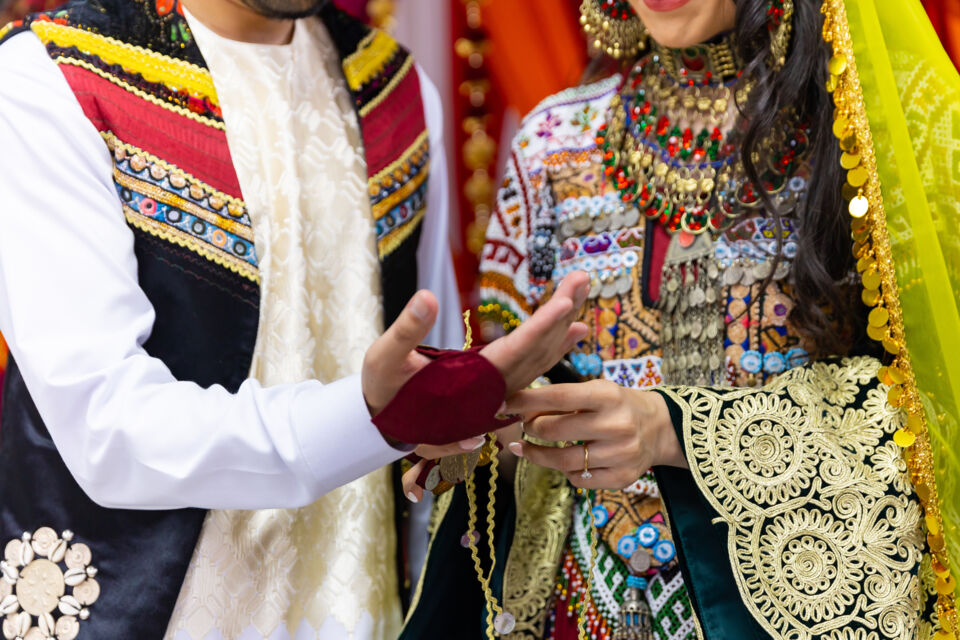Adobe Stock - Photo d'illustration - Un couple afghan resplendissant en tenues traditionnelles lors de la cérémonie du henné, entouré de leurs proches, partageant des moments de joie et de bénédiction avant leur union.