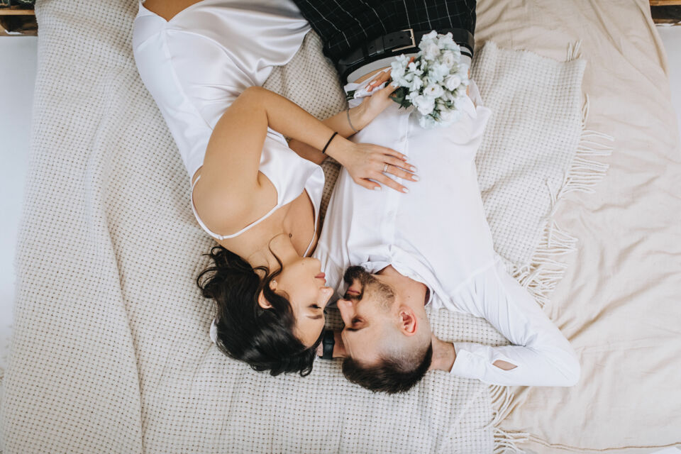 Adobe Stock - Photo d'illustration - Un couple de jeunes mariés amoureux, prêts à se retrouver en toute intimité, mais rattrapés par la fatigue accumulée de cette journée inoubliable.