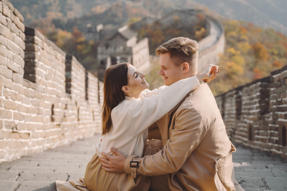 Freepik - Photo d'illustration -&nbsp;Un couple de jeunes mariés profite de leur voyage de noces en Chine, avec la majestueuse Muraille de Chine en arrière-plan, symbole de leur nouvelle aventure commune.