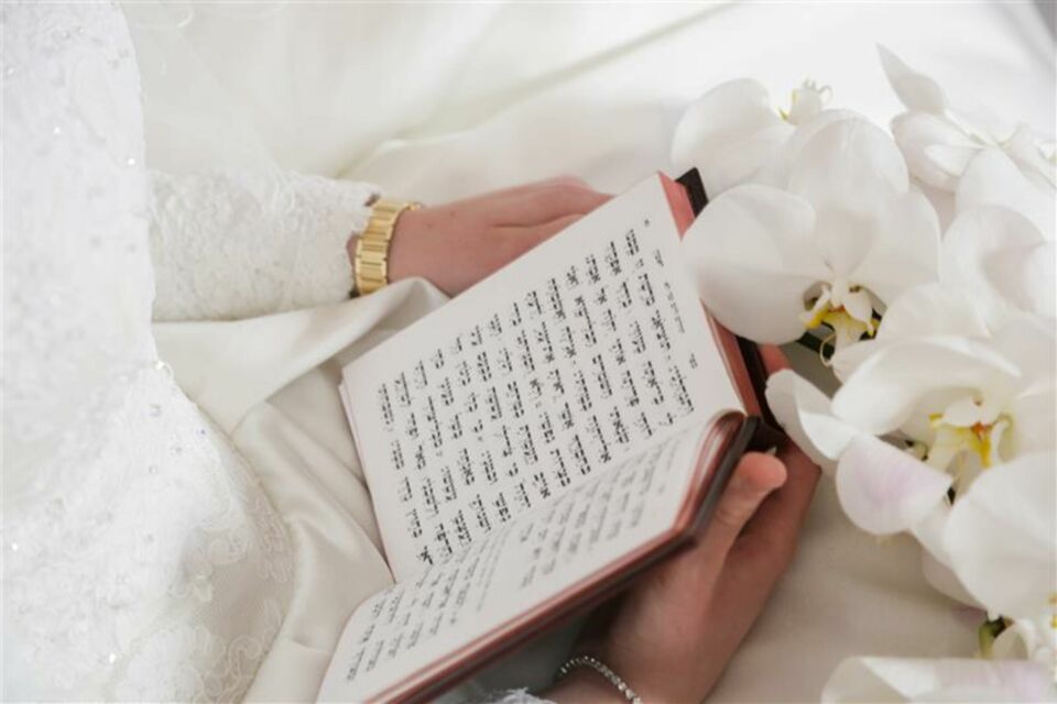 Adobe Stock - Photo d'illustration - Une mariée portant la Torah dans ses mains, symbolisant la profonde connexion spirituelle et les traditions millénaires qui unissent le couple lors de leur mariage juif.