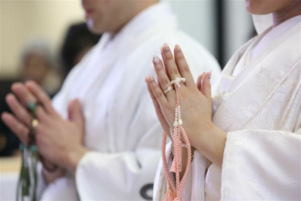 Adobe Stock - Photo d'illustration - Un couple de jeunes mariés bouddhistes échange des vœux empreints de sagesse et de sérénité, entouré de textes sacrés et de symboles spirituels qui bénissent leur union.