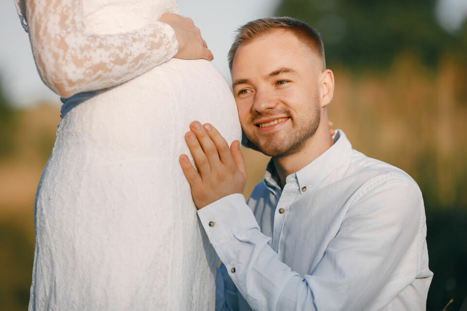 Adobe Stock - Photo d'illustration -&nbsp;Un instant suspendu entre deux promesses : celle du mariage et celle de la vie. Un jeune marié pose tendrement sa tête sur le ventre arrondi de son épouse, vêtus tous deux de leurs habits nuptiaux, incarnant la beauté de l’amour et des nouvelles aventures à venir.