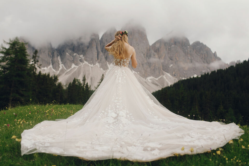 Freepik - Photo d'illustration - De dos, face aux montagnes majestueuses, sa tenue de mariage parfaitement adaptée au cadre naturel sublime l’instant d’éternité qui l'attend.