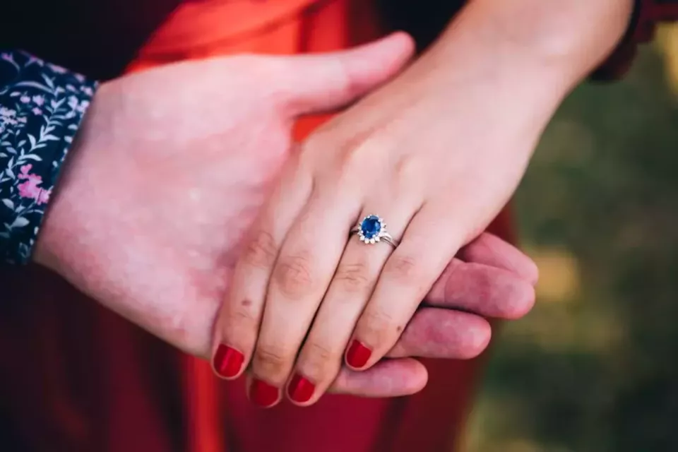 Pexels - Photo d'illustration - Une bague de fiançailles ornée d’un saphir bleu, symbole de fidélité et de sagesse, portée par la promise délicatement tenue par son futur époux. 