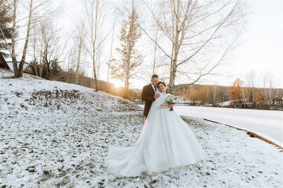 Adobe Stock - Photo d'illustration - Un couple de mariés heureux, entouré par la nature enneigée, capturant l’essence d’un mariage magique et romantique en plein hiver.