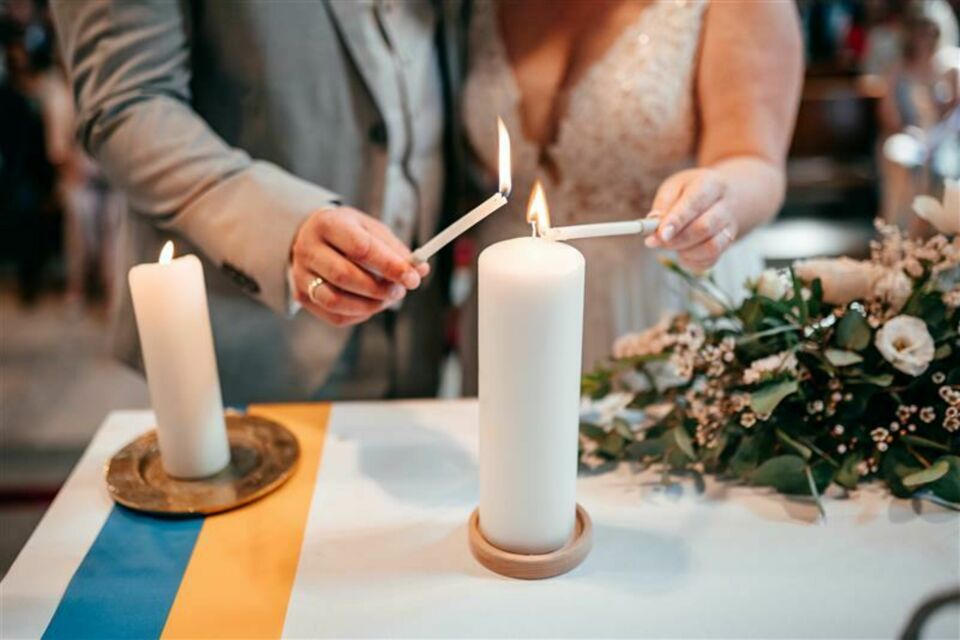 Adobe Stock - Photo d'illustration - Un rituel moderne et symbolique pour les mariés : allumer une bougie commune, représentant l’union de deux vies qui s’entrelacent.