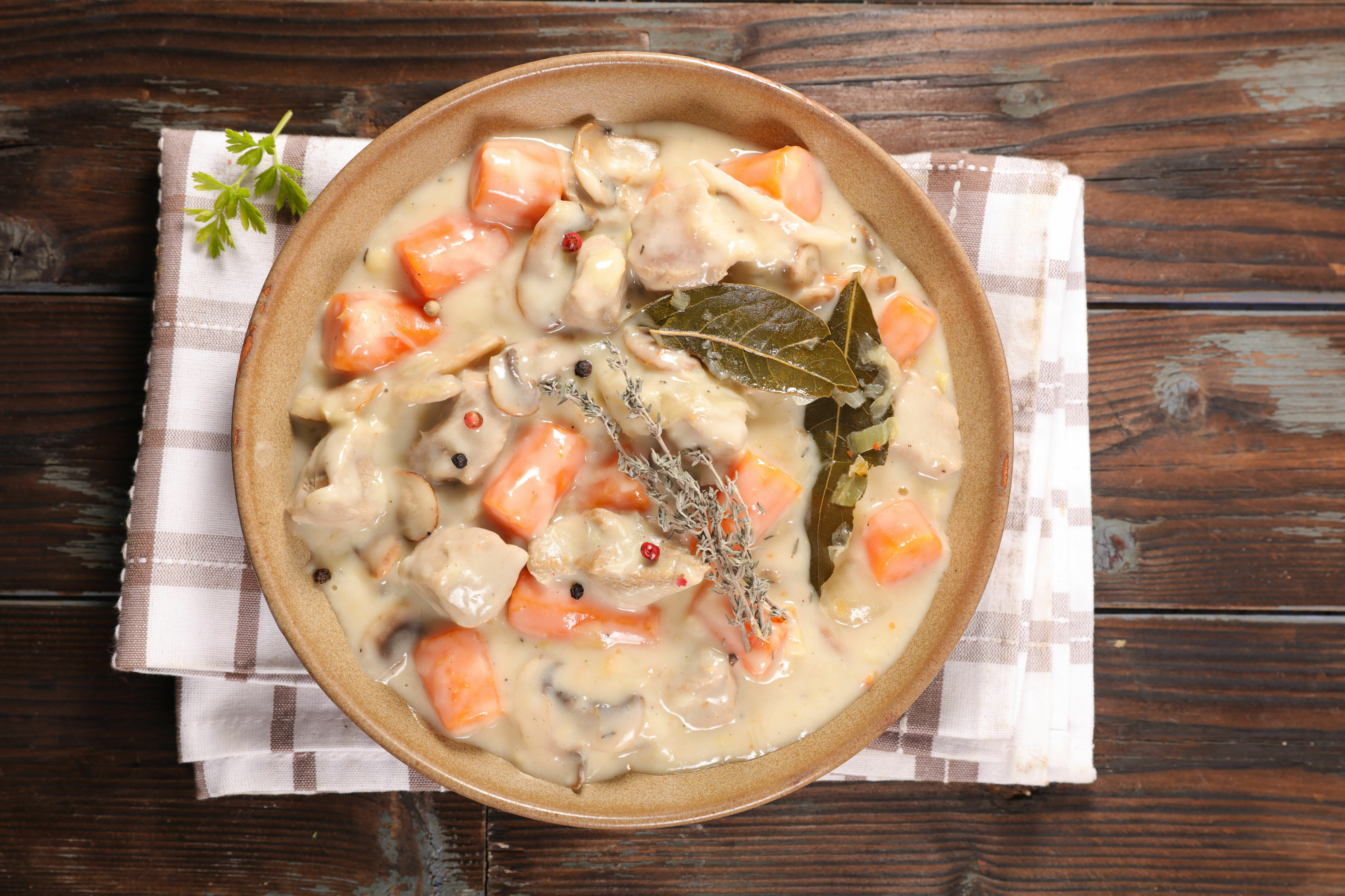 Adobe Stock - Une blanquette - celle-ci peut être de dinde, de veau ou de saumon - aromatisée de feuilles de laurier et de branches de thym, servie dans une assiette.
