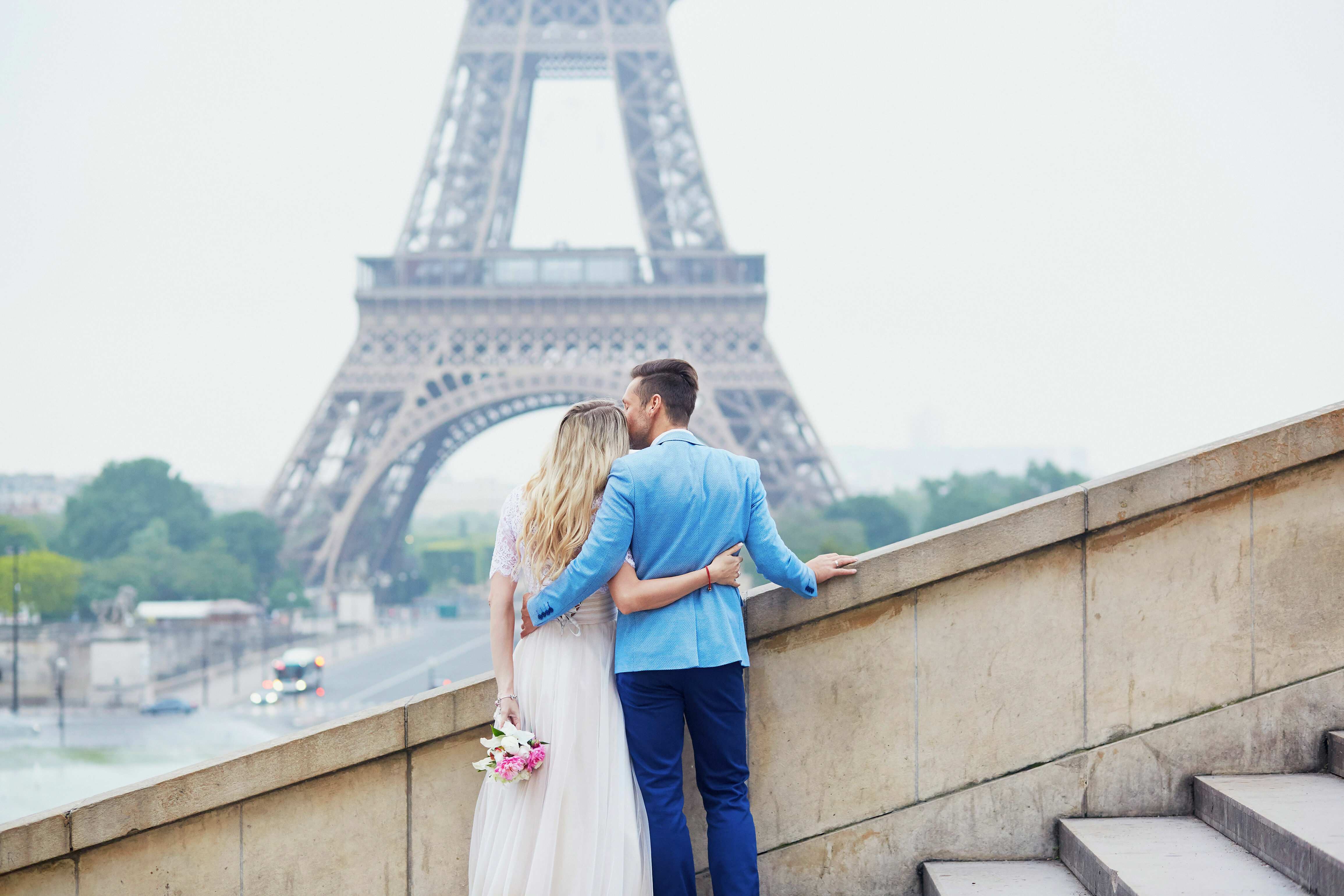 Adobe Stock - Photo d'illustration - Un homme embrassant sa moitié sur front, tournés tous les deux vers la Tour Eiffel.