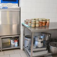 Cuisine vu du lave vaisselle professionnel avec tables de préparation et ces deux chambres froide