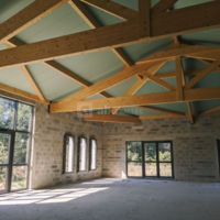 Intérieur avec charpente apparente et grandes baies vitrées pour faire entrer la lumière