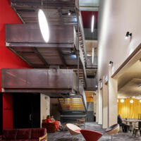 Au centre du cinéma Les Variétés, l’espace vertical, captant en journée un éclairement zénithal et mis en lumière par des suspensions évoquant la toile d’écran lumineuse, accueille un escalier sculptu