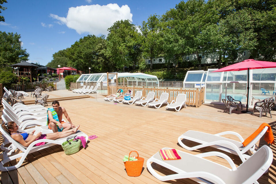 Une grande terrasse en bois en bord de piscine