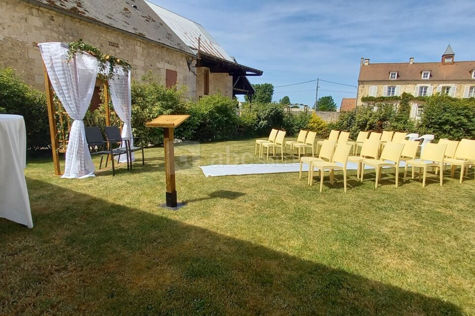 Cérémonie installée au jardin du domaine, chaises, tapis, arche, banc avec coussins