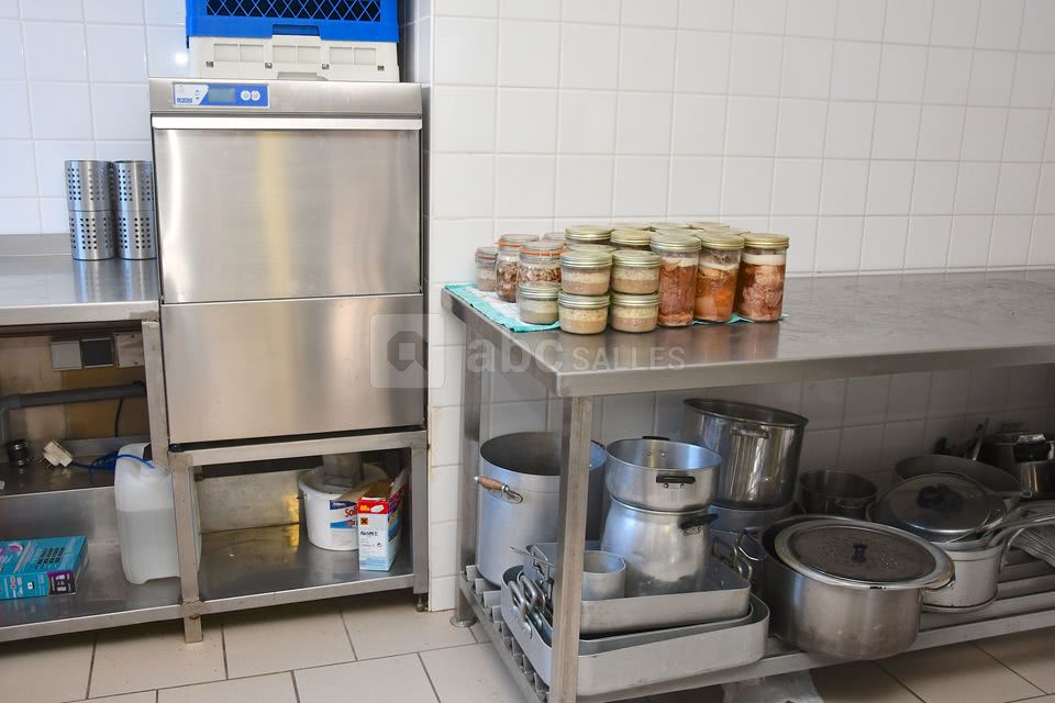 Cuisine vu du lave vaisselle professionnel avec tables de préparation et ces deux chambres froide