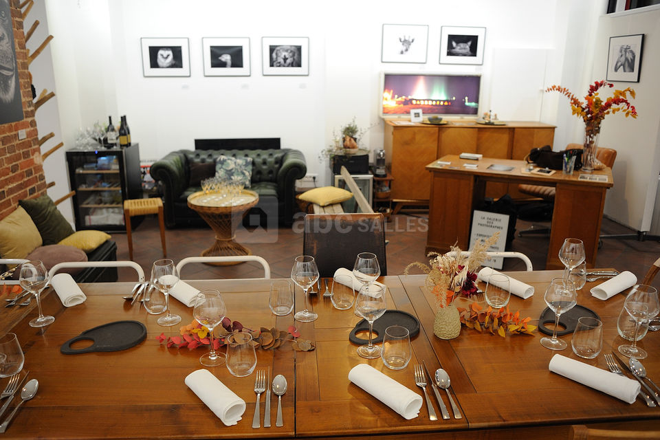 Table dressée et espace salon au fond pour un repas gastronomique dans la galerie