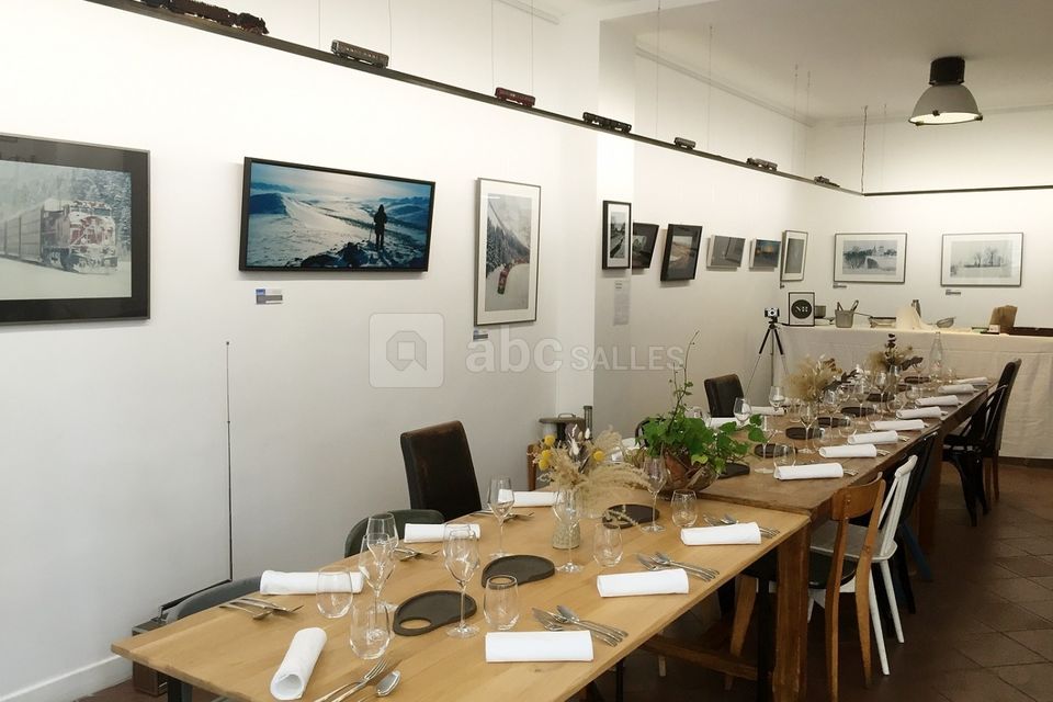 Tables dressées et espace de travail au fond pour un repas gastronomique dans la galerie